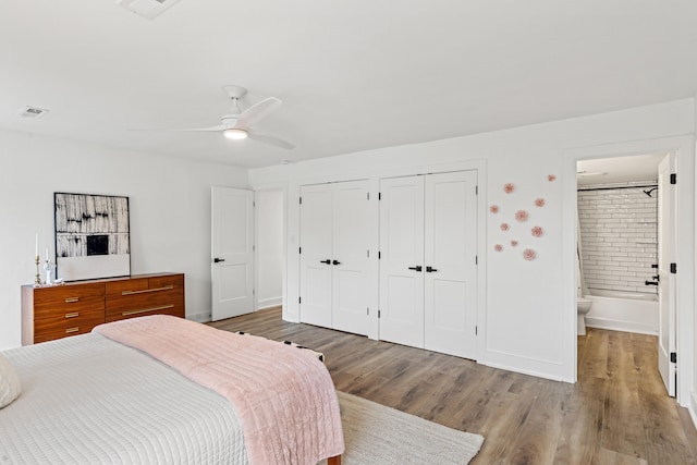 bedroom featuring ensuite bathroom, ceiling fan, light wood-type flooring, and multiple closets