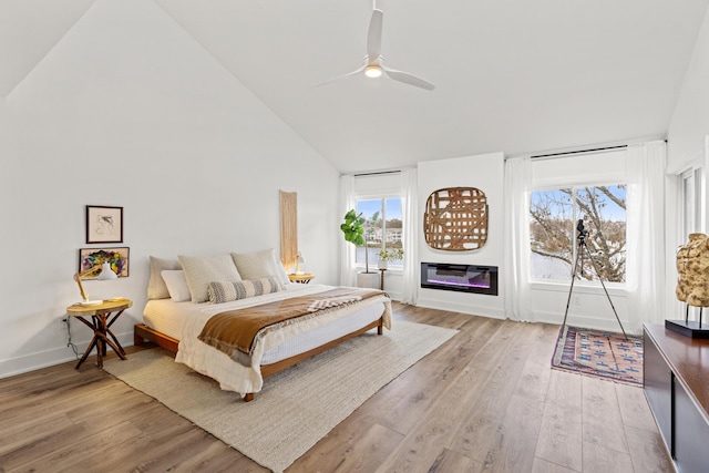 bedroom with multiple windows, ceiling fan, lofted ceiling, and light wood-type flooring