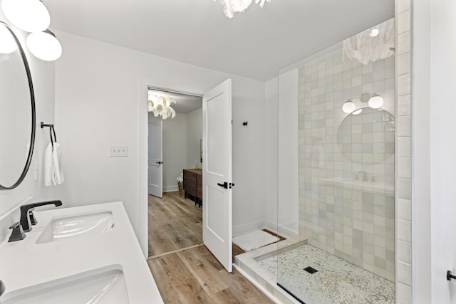 bathroom featuring hardwood / wood-style floors, vanity, and a tile shower