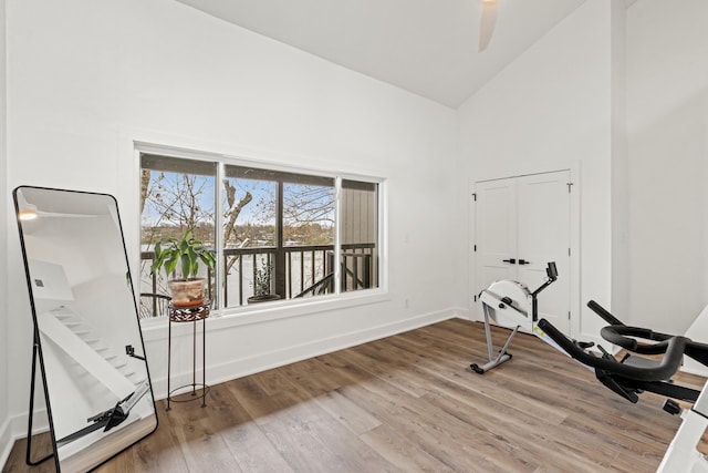 exercise room featuring ceiling fan, high vaulted ceiling, and wood-type flooring