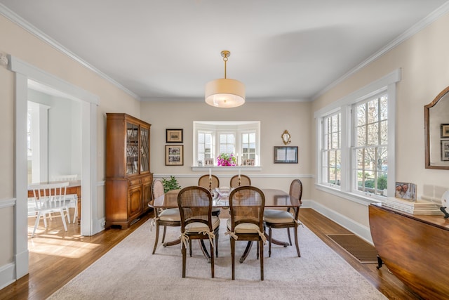 dining area with light hardwood / wood-style flooring and ornamental molding