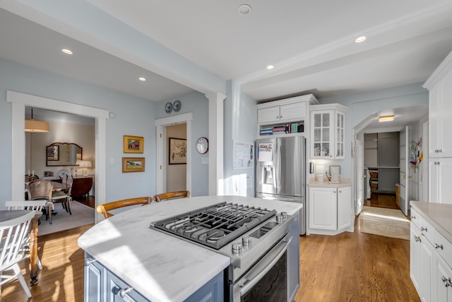 kitchen featuring white cabinets, stainless steel appliances, a kitchen island, and light hardwood / wood-style flooring