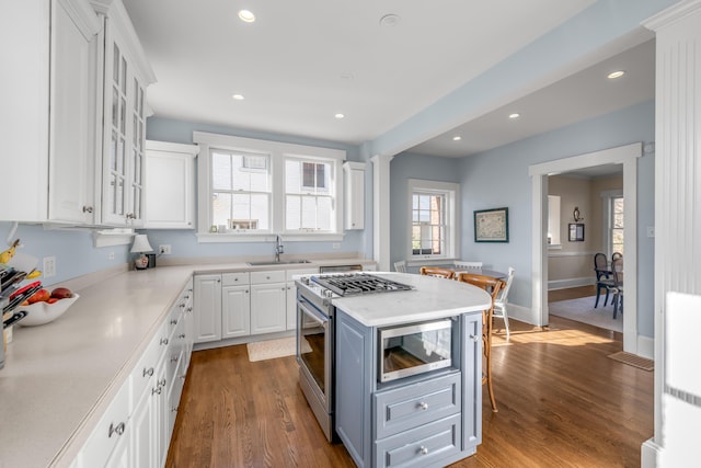 kitchen featuring sink, white cabinets, appliances with stainless steel finishes, a kitchen island, and hardwood / wood-style flooring