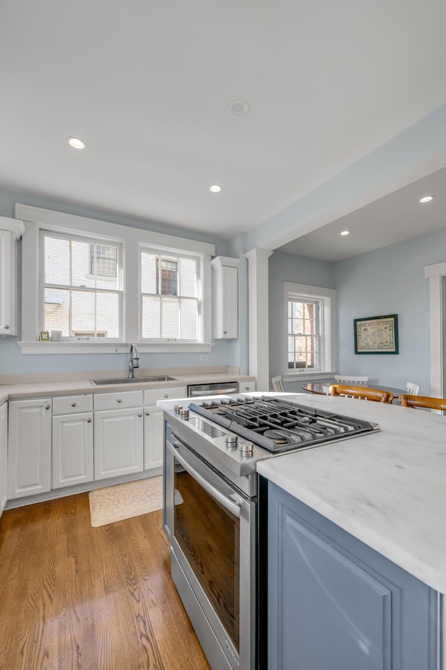 kitchen featuring appliances with stainless steel finishes, white cabinetry, light hardwood / wood-style flooring, and sink