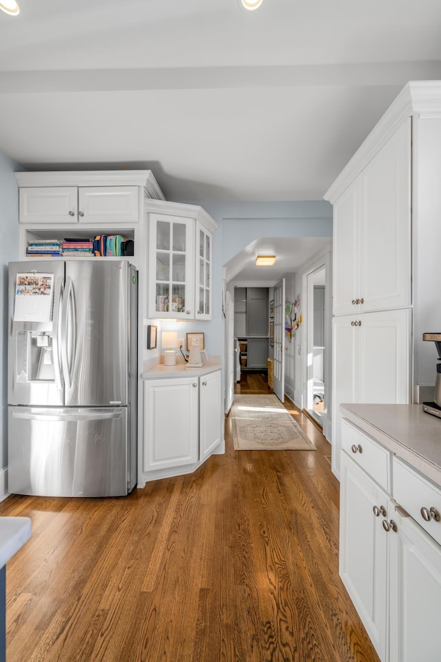 kitchen with stainless steel fridge, white cabinetry, and wood-type flooring