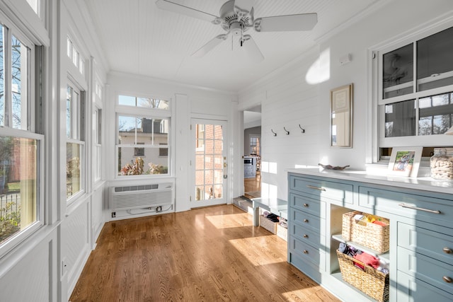 sunroom featuring ceiling fan, an AC wall unit, and a wealth of natural light