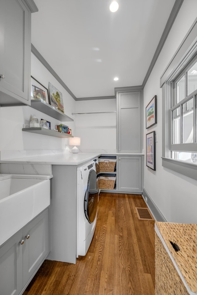 laundry area with cabinets, ornamental molding, sink, hardwood / wood-style flooring, and independent washer and dryer