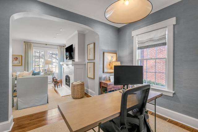 office area with hardwood / wood-style floors, a brick fireplace, and crown molding