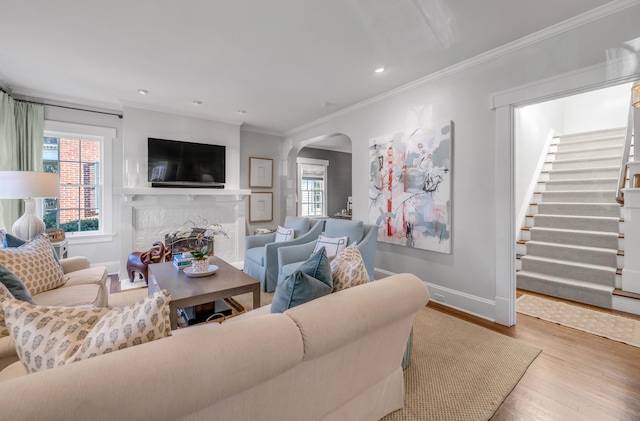 living room with a fireplace, light hardwood / wood-style flooring, and crown molding