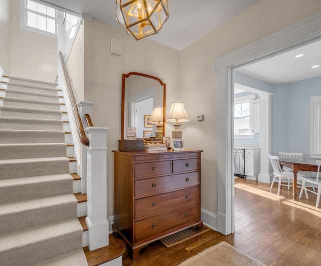 staircase with hardwood / wood-style floors and a chandelier