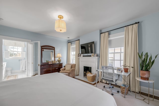 bedroom featuring light carpet, connected bathroom, and multiple windows