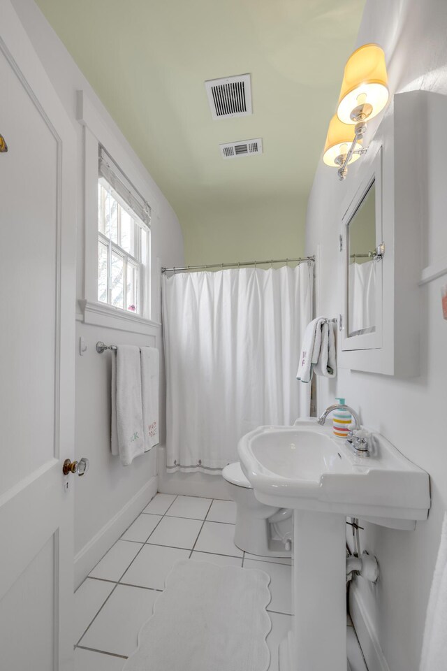 bathroom featuring tile patterned flooring, shower / bath combination with curtain, and toilet