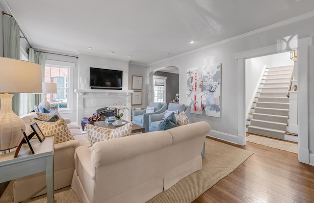 living room featuring a fireplace, hardwood / wood-style floors, and crown molding