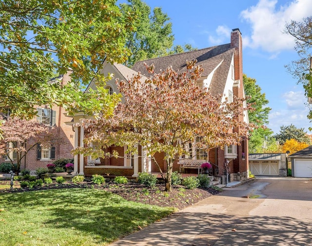 view of front of property with a front yard, an outdoor structure, and a garage