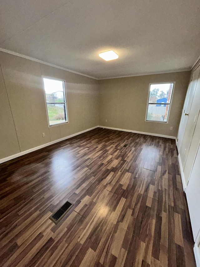 unfurnished room with dark hardwood / wood-style floors, ornamental molding, and a wealth of natural light