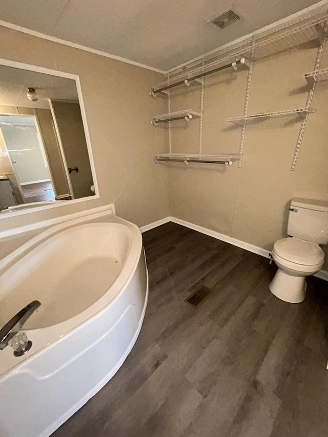 bathroom featuring toilet, ornamental molding, and hardwood / wood-style flooring