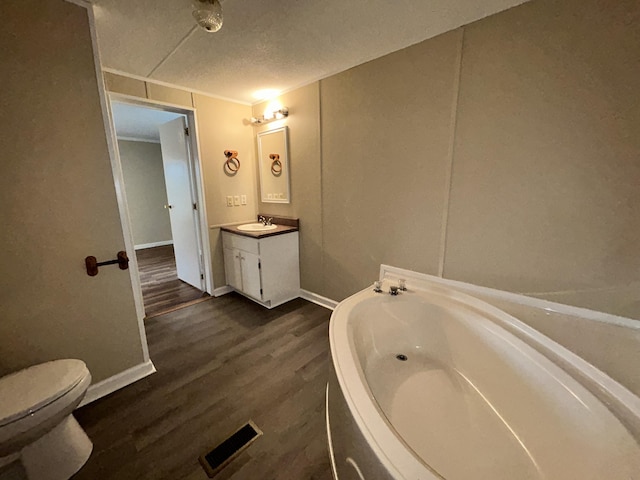 bathroom featuring vanity, a bathing tub, hardwood / wood-style flooring, toilet, and a textured ceiling