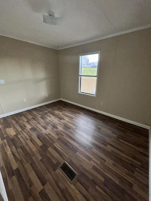 empty room with ornamental molding and dark wood-type flooring