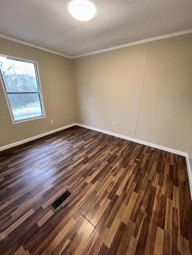 empty room with crown molding, dark wood-type flooring, and a textured ceiling