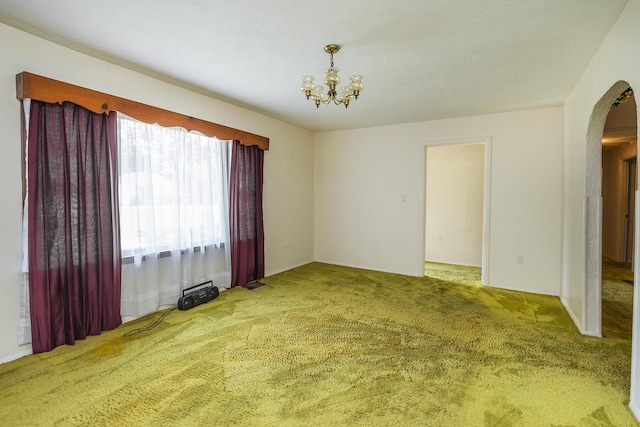 carpeted spare room featuring an inviting chandelier