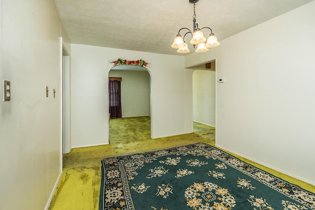 unfurnished room featuring a textured ceiling and a chandelier