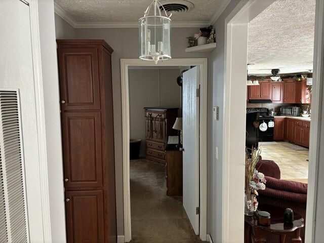 hall featuring a textured ceiling, carpet flooring, and crown molding