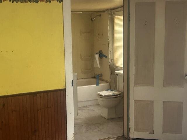 bathroom featuring toilet, wooden walls, and bathing tub / shower combination