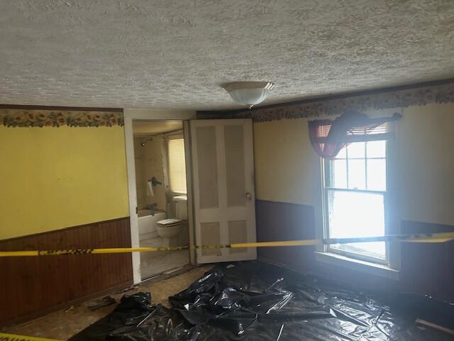 empty room featuring a textured ceiling and wood walls