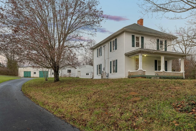 property exterior at dusk with a lawn and a porch