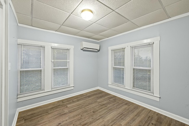 spare room with hardwood / wood-style floors, a drop ceiling, and a wall unit AC