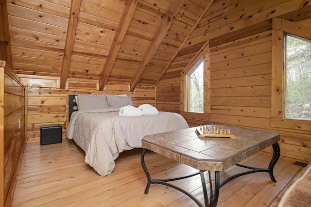 bedroom with lofted ceiling with beams, light hardwood / wood-style floors, wooden ceiling, and wooden walls