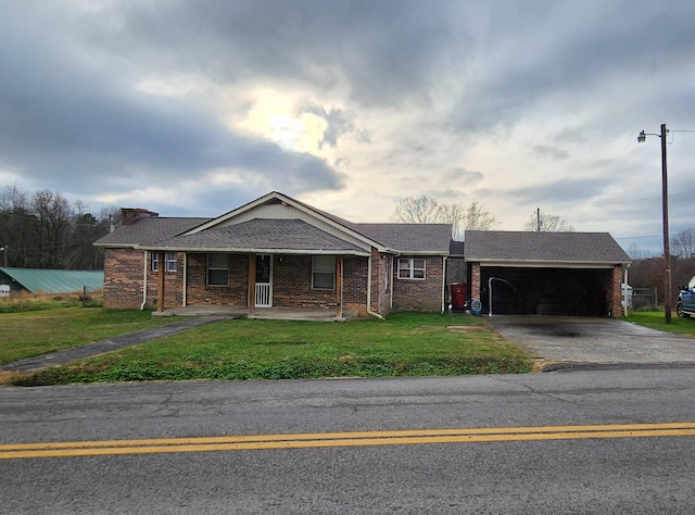 single story home with aphalt driveway, a front lawn, an attached garage, and brick siding