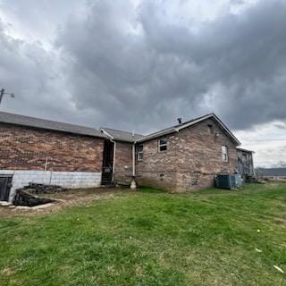 back of property featuring brick siding, a lawn, and central air condition unit