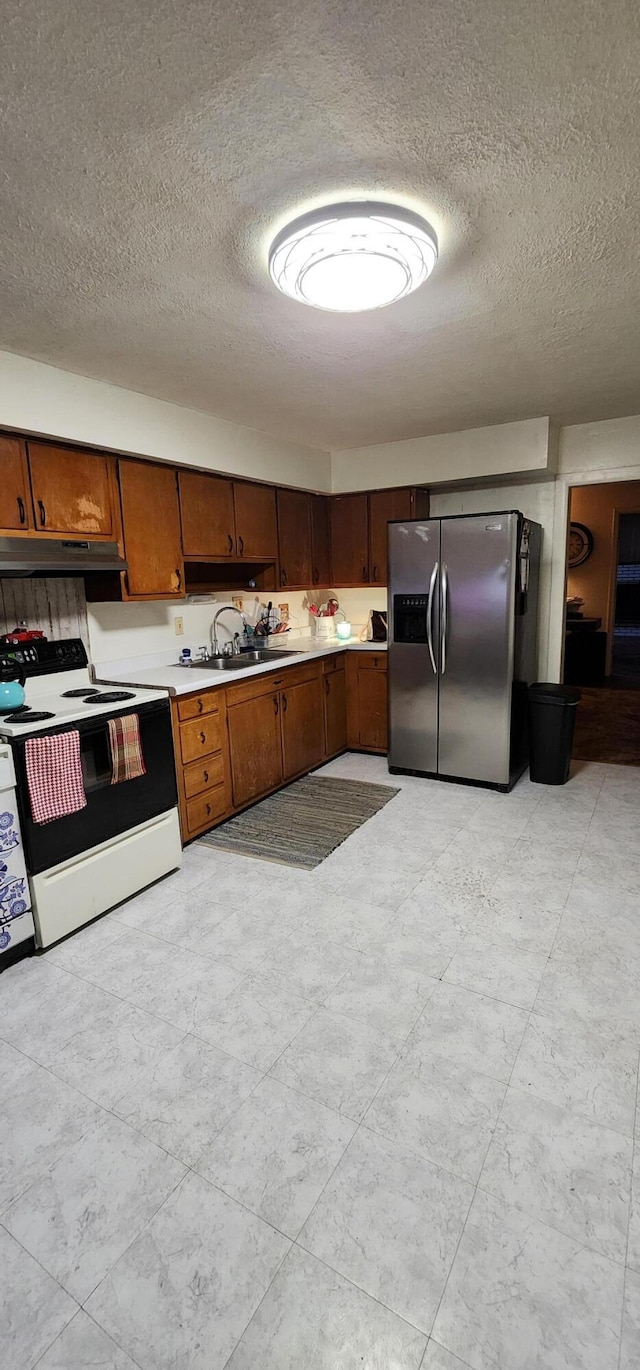 kitchen with stainless steel fridge, a textured ceiling, white electric stove, and sink