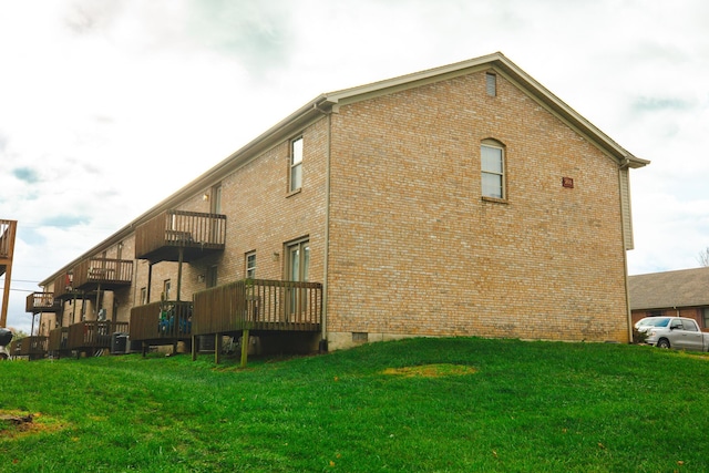 rear view of house featuring a lawn, a balcony, and central air condition unit