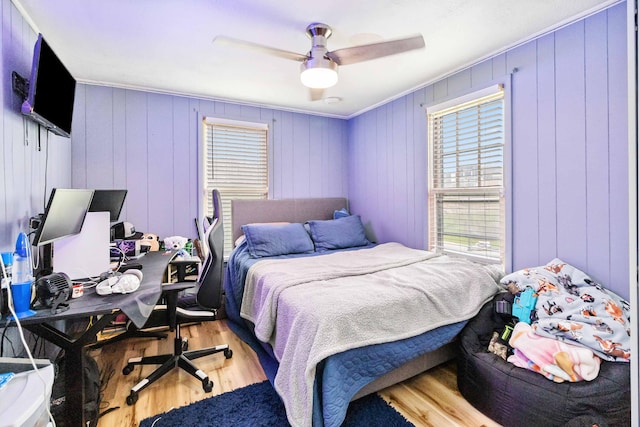 bedroom featuring hardwood / wood-style floors, ceiling fan, ornamental molding, and wood walls