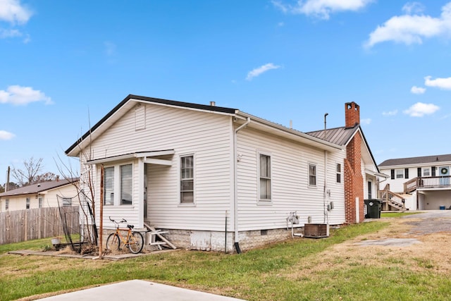 rear view of property featuring a lawn and central AC