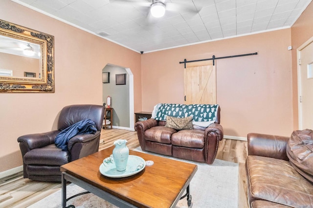 living room featuring a barn door, hardwood / wood-style floors, and ornamental molding