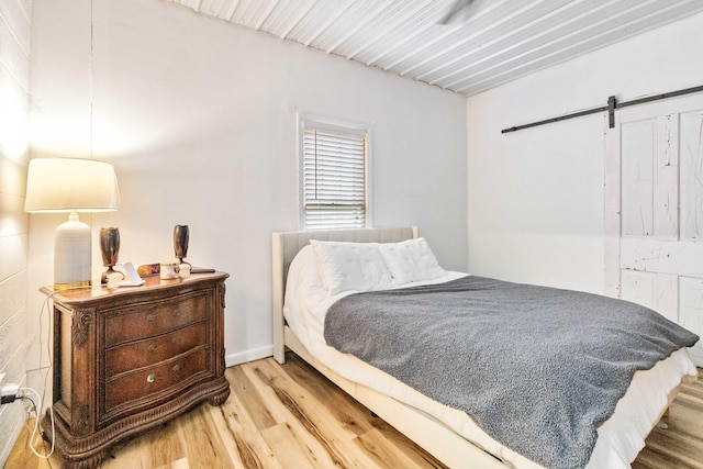 bedroom with a barn door and light hardwood / wood-style flooring