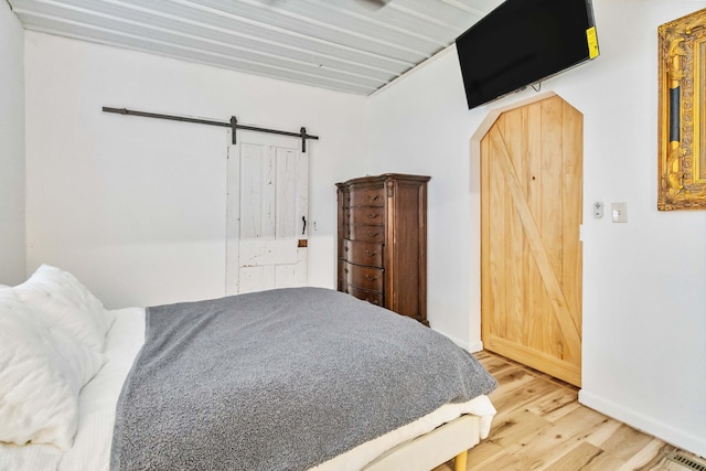 bedroom featuring a barn door and wood-type flooring