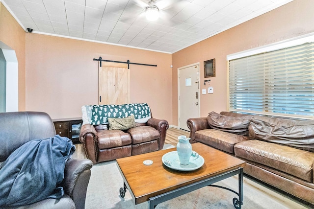 living room featuring a barn door, wood-type flooring, and ornamental molding