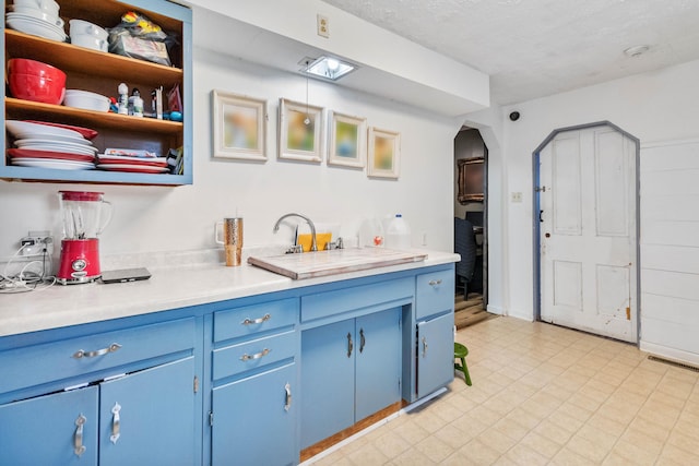 kitchen with blue cabinetry and a textured ceiling