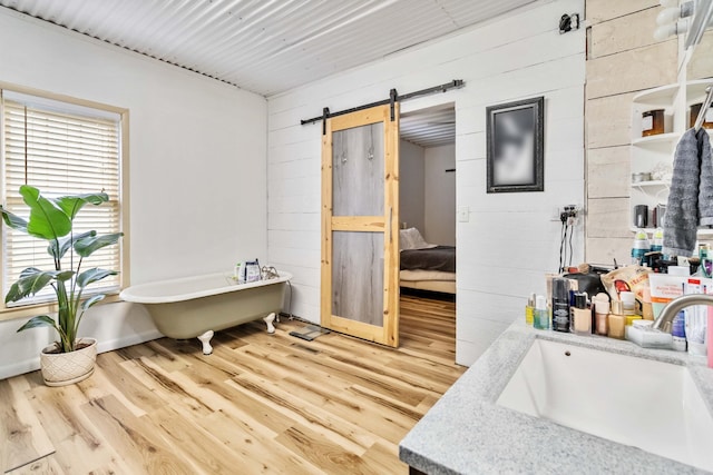 bathroom with hardwood / wood-style flooring, wood walls, sink, and a tub