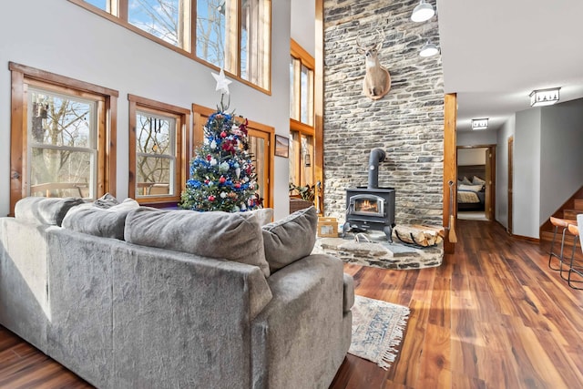 living room with a wood stove, dark hardwood / wood-style flooring, and a towering ceiling