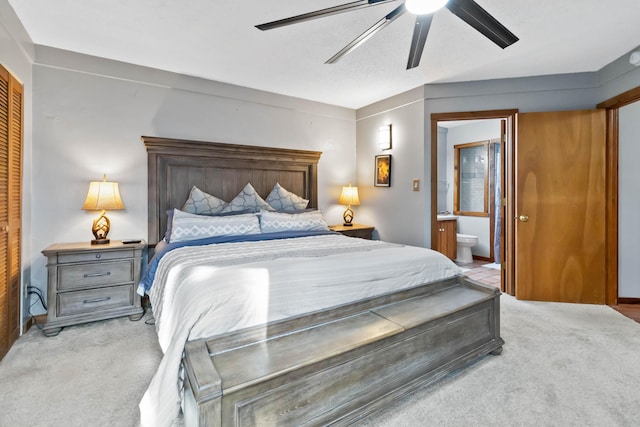 carpeted bedroom featuring ceiling fan, a closet, and ensuite bath