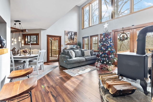 living room featuring plenty of natural light, dark hardwood / wood-style flooring, a wood stove, and a high ceiling