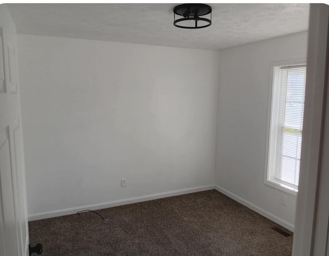 carpeted empty room featuring baseboards, a textured ceiling, and visible vents