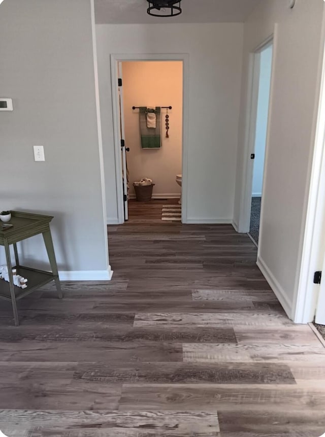 hall with baseboards and wood finished floors
