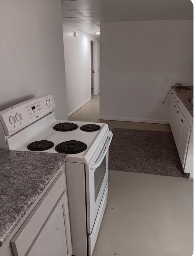 kitchen featuring white cabinets, electric range, a paneled ceiling, and finished concrete flooring