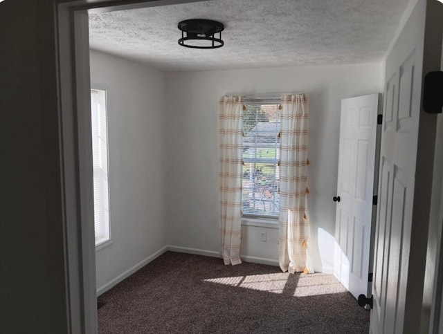 unfurnished room with dark carpet and a textured ceiling